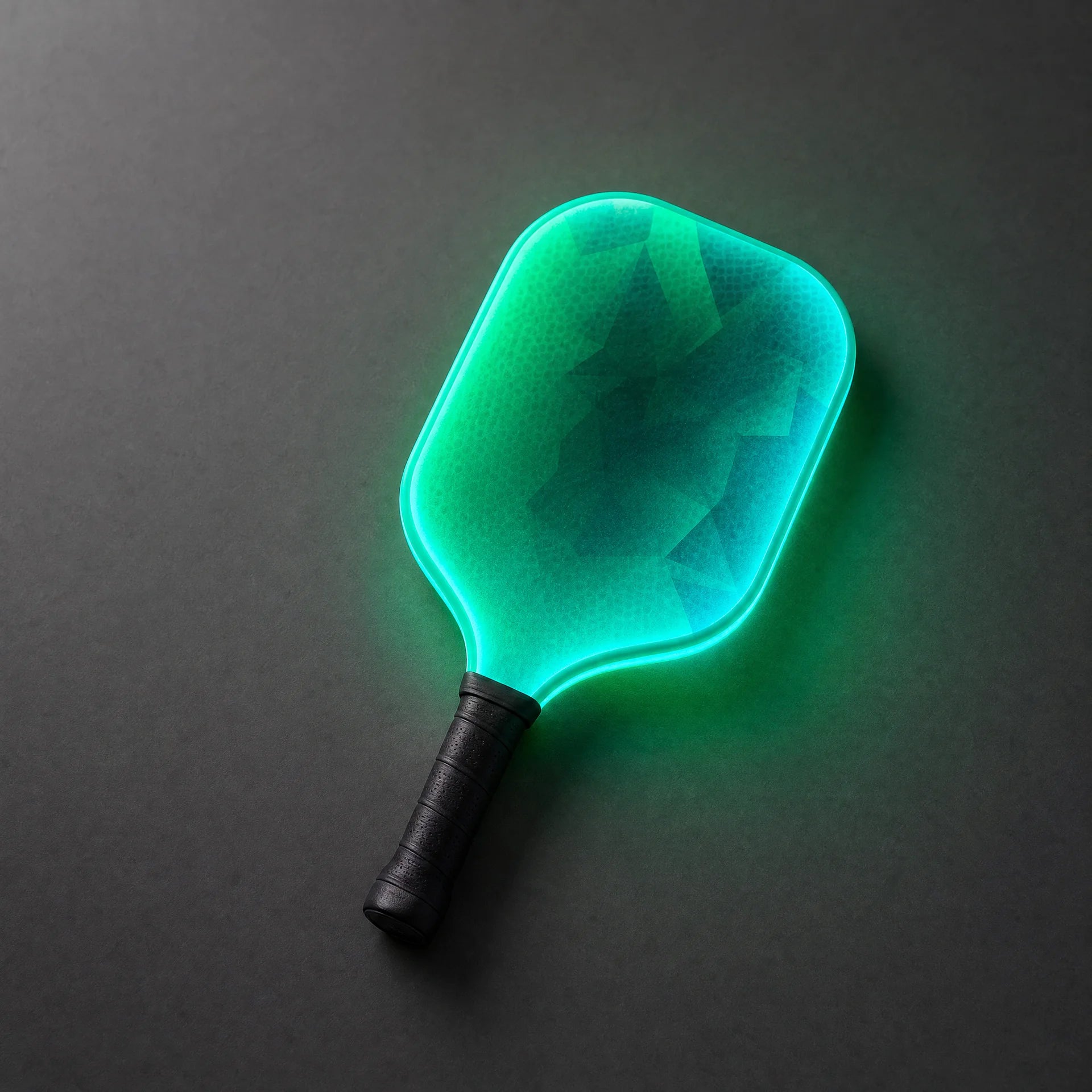 Green light-up pickleball paddle on a charcoal surface