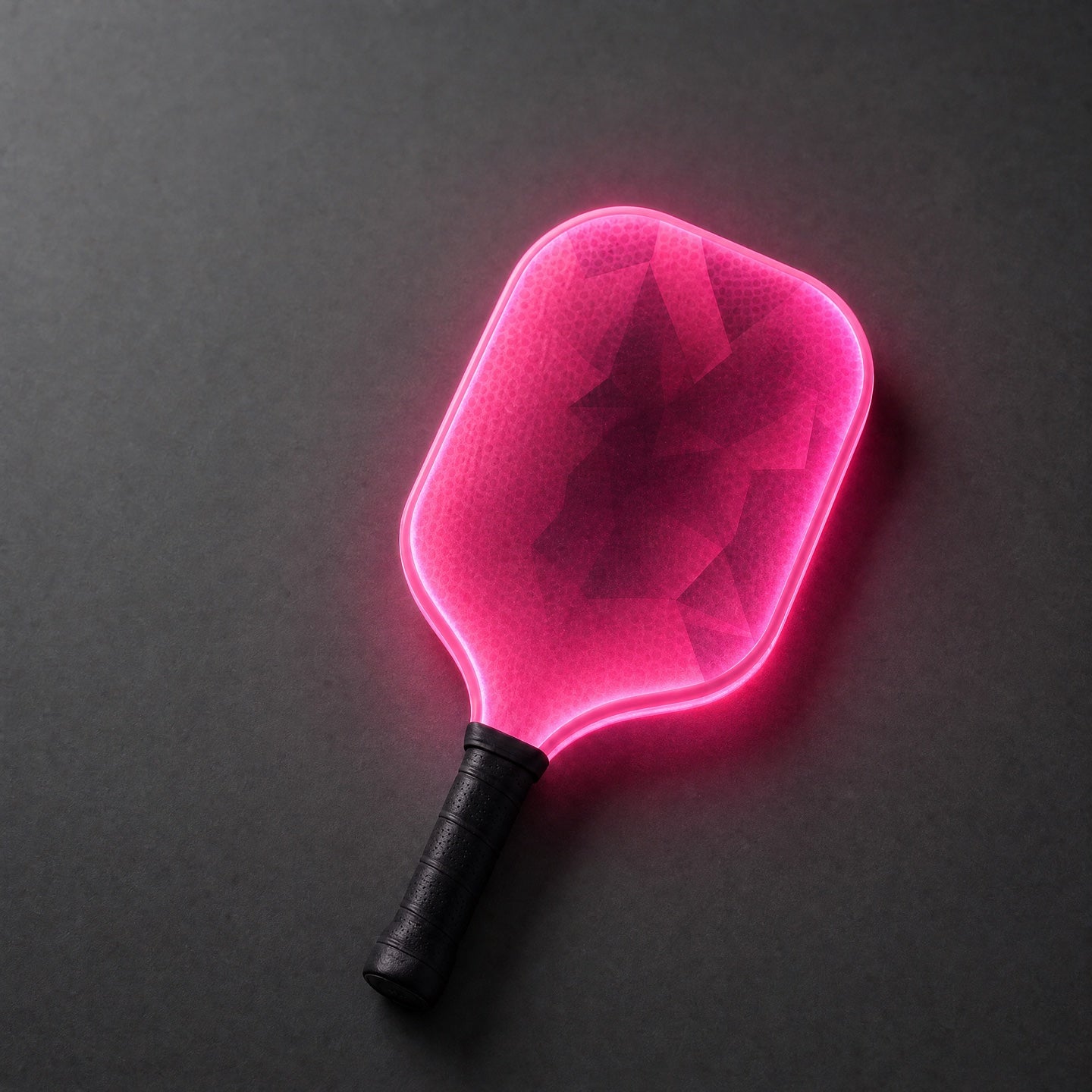 The RGB pickleball paddle glowing pink on a charcoal surface
